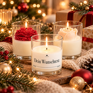 Drei festlich dekorierte LILIEN Duftkerzen im Glas mit Wunschtext, Tannenzweigen, Weihnachtslichtern und Geschenkverpackungen